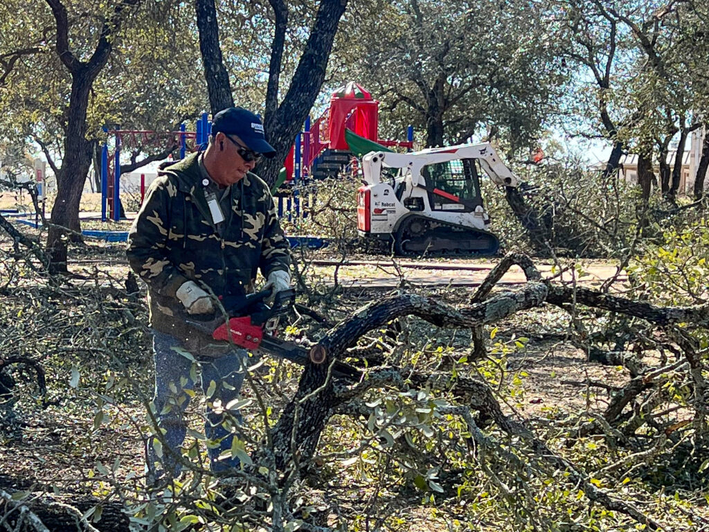 A Grounds crew member works to clear tree debris