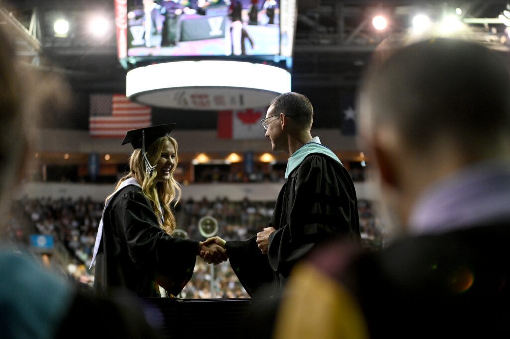 LISD High School Graduate shaking hands with Superintendent Gearing on stage.