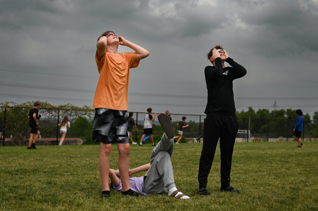 Students wearing safety glasses stare up at the eclipse event