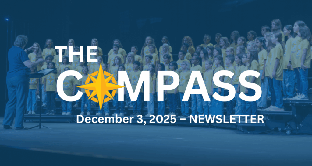 A children's choir performs in an auditorium while a conductor leads them.